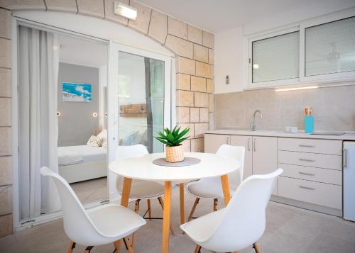 een keuken met een witte tafel en witte stoelen bij Villa Rajski Dvor in Bol