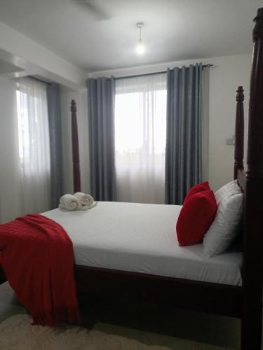 a bedroom with a bed with red pillows and a window at Rina Crystal Accommodation in Mombasa