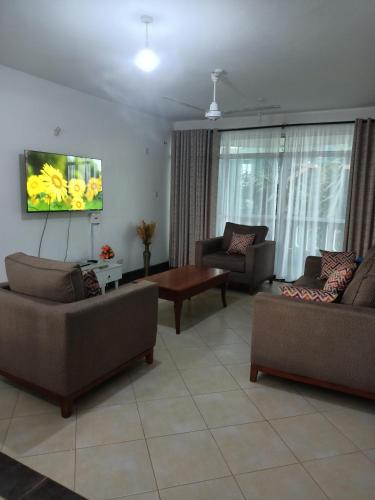 a living room with couches and a flat screen tv at Rina Crystal Accommodation in Mombasa