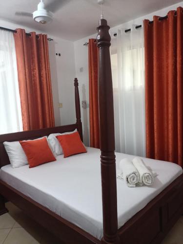a bedroom with a bed with orange and white pillows at Rina Crystal Accommodation in Mombasa