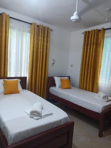 two beds in a room with yellow curtains at Rina Crystal Accommodation in Mombasa