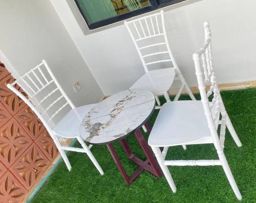 two white chairs and a table in a room at Homie flat with airport view in Entebbe