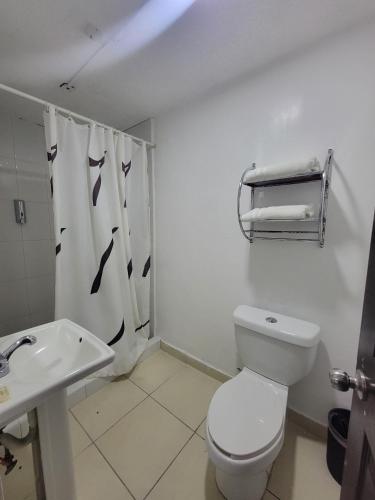 a white bathroom with a toilet and a sink at Hotel Paraiso Inn in Tehuacán