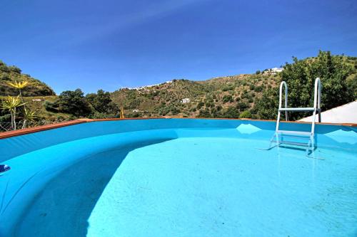 een blauw zwembad met een stoel erin bij Finca el Almendro Archez in Árchez