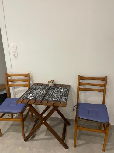 una mesa de madera con 2 sillas y una mesa con una planta. en Tourlos House en Andiparos