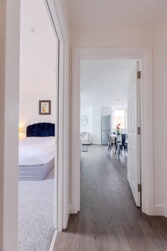 a white bedroom with a bed and a dining room at Vertigo Boutique Sleeps 4 London in Kingston upon Thames