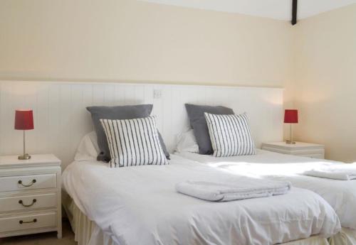 Duas camas com lençóis brancos e almofadas num quarto em Pond Cottage em Shaftesbury