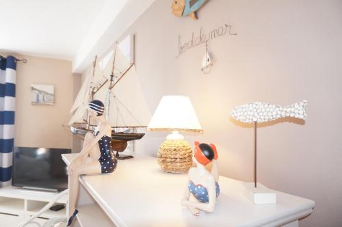 two dolls sitting on a table with a lamp at Le 33 Cour Normande - Appartement 2 chambres - 2 à 4 personnes - coeur Cabourg in Cabourg