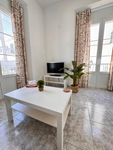 a living room with a white table and a tv at Cabildo 1 in Sanlúcar de Barrameda