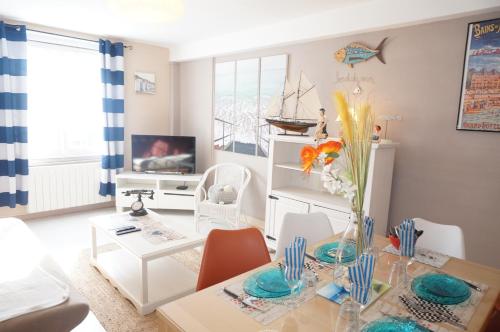 a living room with a dining room table with a vase of flowers at Le 33 Cour Normande - Appartement 2 chambres - 2 à 4 personnes - coeur Cabourg in Cabourg