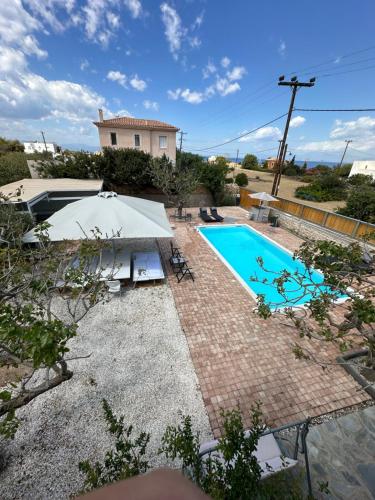 a swimming pool with an umbrella next to a house at SolMar Aegina with private pool - jacuzzi in Khlóï