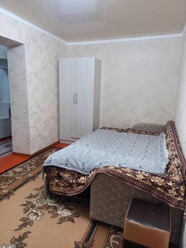 een slaapkamer met een bed in de hoek van een kamer bij Mahabat in Karakol
