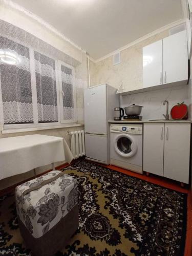 uma pequena cozinha com um fogão e uma máquina de lavar roupa em Mahabat em Karakol