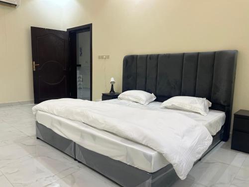 - un grand lit avec une tête de lit noire dans une chambre dans l'établissement شليه, à Hafr Al Baten
