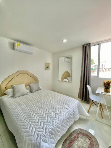 卡塔赫納的住宿－Casa Jardin，卧室配有一张白色大床和一张书桌
