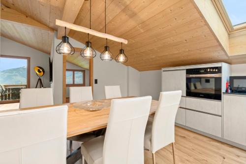 a dining room with a wooden table and white chairs at Stilvolle 4.5 Zimmer Wohnung nahe der Talstation in Vella