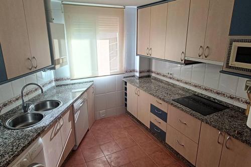 una cocina con armarios blancos y fregadero en Apartamento con terraza 2 hab., en Alcalá la Real