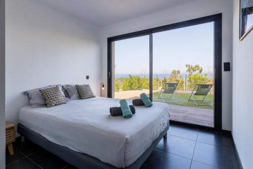 une chambre avec un lit et une grande fenêtre en verre dans l'établissement Villa Kalinas Corse 4 étoiles, à Sari-Solenzara