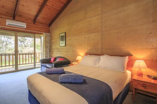 a bedroom with a large bed and a chair at The Koorabup Motel in Denmark