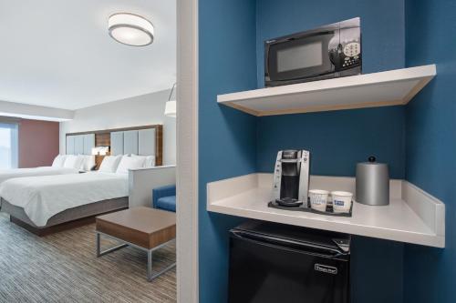 a hotel room with a bed and a tv on a wall at Holiday Inn Express & Suites Clinton by IHG in Clinton