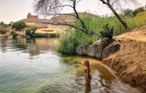 Una donna in piedi nell'acqua vicino a un fiume di Private transportation a Aswan