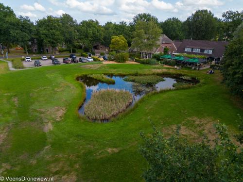 eine Aussicht über einen Golfplatz mit einem Teich in der Unterkunft Herberg de Loohoeve in Schoonloo