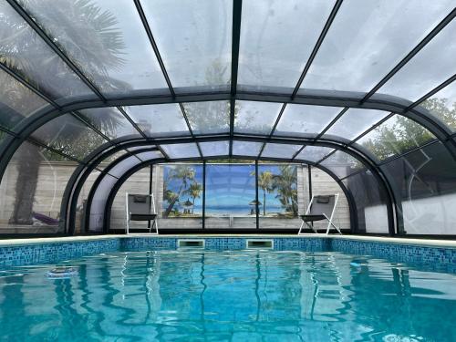 an indoor swimming pool with a glass ceiling at Maison 10 pers avec piscine chauffée et spa in Surzur