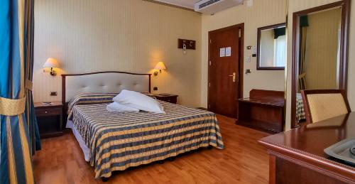 a hotel room with a bed with two pillows on it at Hotel Benaco Garda ***S in Garda
