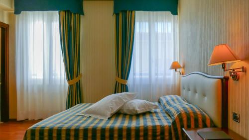 a bedroom with a bed with pillows on it at Hotel Benaco Garda ***S in Garda