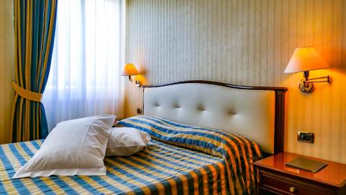 a bedroom with a bed with two pillows and a table at Hotel Benaco Garda ***S in Garda