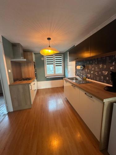 a kitchen with wooden floors and a light hanging from a ceiling at Le coup de c’Heurt duplex 100m de la mer 8 personnes in Le Portel