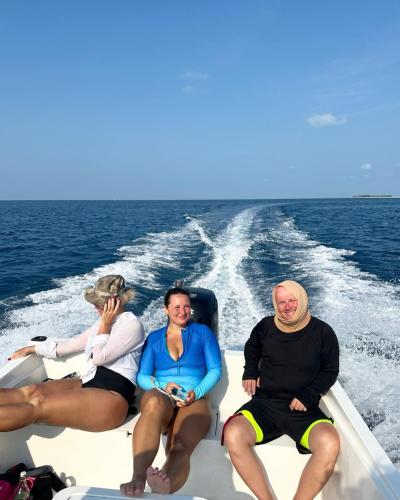 three people sitting on a boat in the water at Atholhu Residence in Fehendhoo