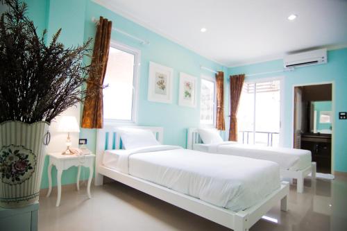 a blue bedroom with two beds and a vase with a plant at Boonsiri Boutique Hotel in Si Sa Ket