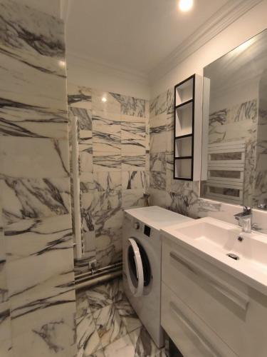 une salle de bain avec un lavabo et une machine à laver dans l'établissement Appart proche plage pied dans l'eau avec terrasse jardin vue sur le bassin depuis la terrasse, à Arcachon