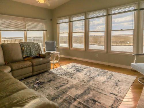 ein Wohnzimmer mit einem Sofa und einigen Fenstern in der Unterkunft Amazing Views! Bhw Lagoonfront Beauty! in Manahawkin