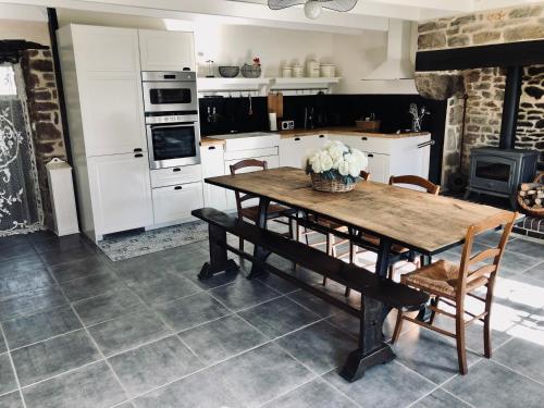 une cuisine avec une table en bois, des chaises et des appareils électroménagers dans l'établissement Gite Cottage Le Giré, à Hudimesnil