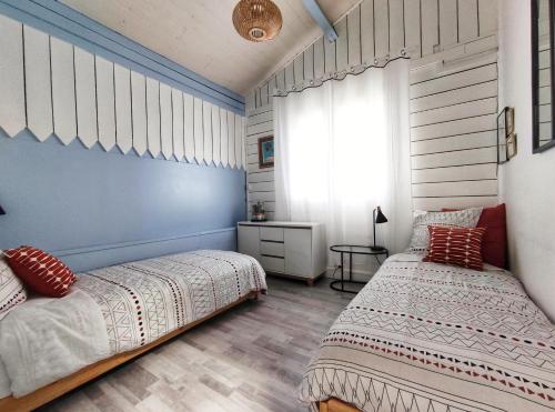 een slaapkamer met 2 bedden en een raam bij La Caravelle - Chalet t2 climatisé lit queen size ou twin in Tarbes