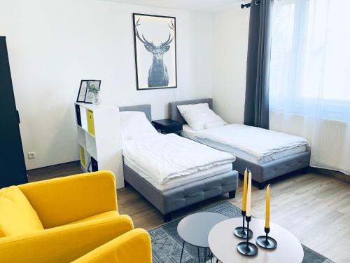 sala de estar con 2 camas y silla amarilla en Yellow&Black NEU Designer Apartment Bielefeld City WLAN kostenloser Parkplatz, en Bielefeld