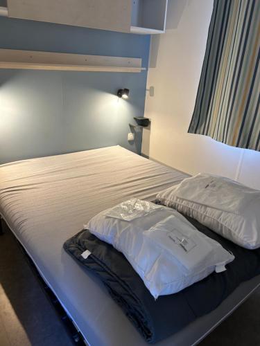 un lit avec des draps blancs et une chemise dessus dans l'établissement Camping la palmeraie 4* mobil home 3 chambres-6personnes, à Torreilles
