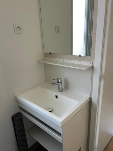 une salle de bain avec un lavabo blanc et un miroir dans l'établissement Camping la palmeraie 4* mobil home 3 chambres-6personnes, à Torreilles