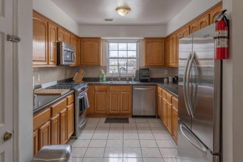 uma cozinha com armários de madeira e um frigorífico de aço inoxidável em Spacious 3B Oasis near Manhattan - 28 mins to NYC em Jersey City