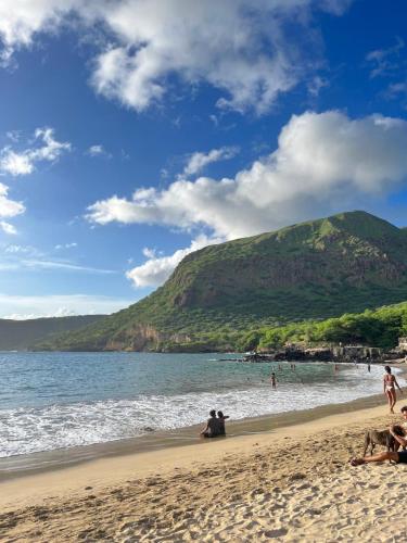 a group of people on a beach with a mountain at Sea View & Balcony Modern Apartment in Pedra Badejo in Pedra Badejo