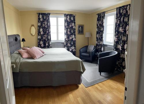 um quarto com uma cama, uma cadeira e janelas em Hotell Laurentius em Strängnäs