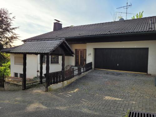 a white house with a black garage door at Am Zimmerkopf in Hermersberg