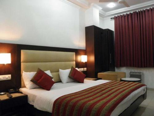 a hotel room with a large bed with red curtains at Hotel Chanchal Continental in New Delhi