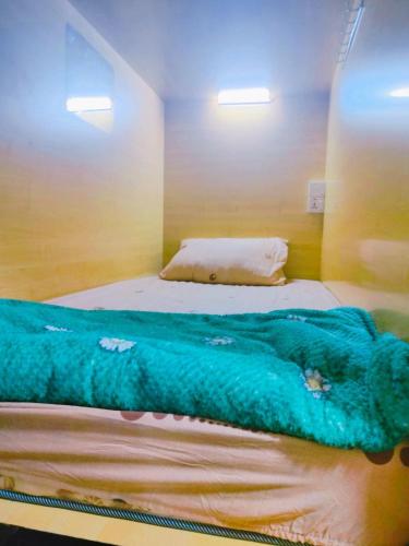 a bedroom with a blue blanket on a bed at Pleasure Pod Hostel Rolla Street in Dubai