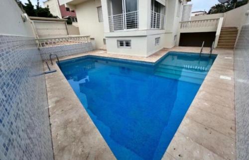a large blue swimming pool in front of a house at Villa avec piscine privée in El Jadida