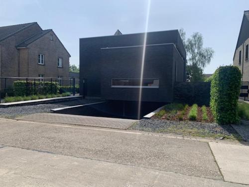 a black house with a building in a yard at 't Veldje in Tongeren
