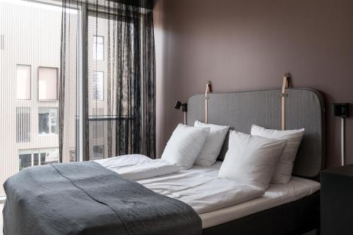 a bedroom with a bed with white pillows and a window at The Pier apartments by Daniel&Jacob's in Copenhagen