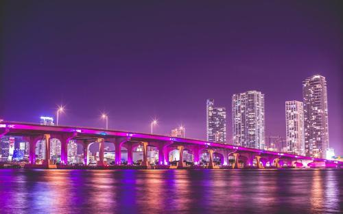 uma ponte sobre a água com uma cidade à noite em Mokulele em Miami